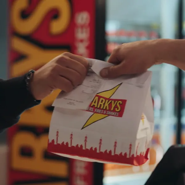 Customer receiving a takeaway bag with a Yoco receipt at Sparkys Burgers, Fries & Shakes.