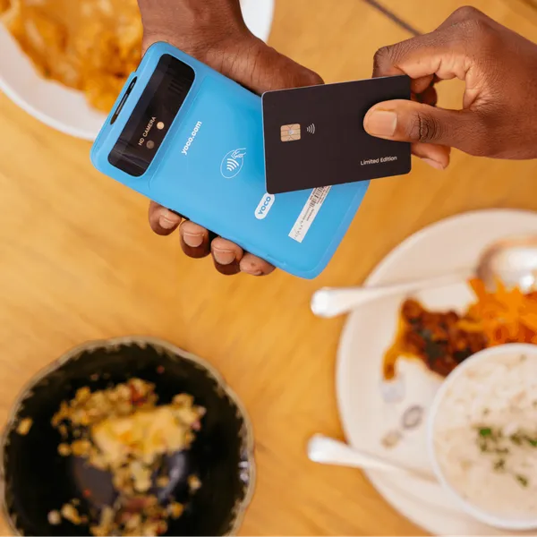 Customer making a contactless payment with a Yoco Khumo card machine at a restaurant table.