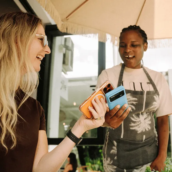 Customer making a payment while interacting with a staff member using a Yoco handheld POS.