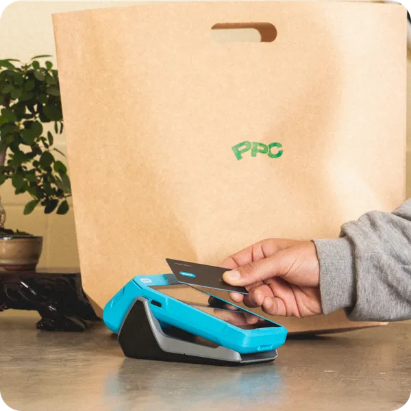 Customer making a card payment with a Yoco Khumo card machine at a clothing store checkout.