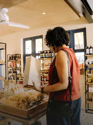 Customer selecting fresh bread in a bright food and beverage shop.