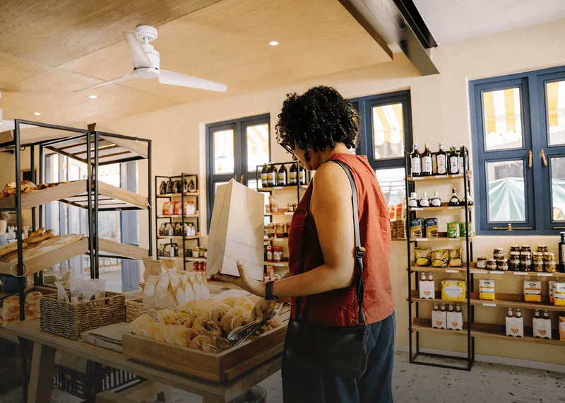 Customer selecting fresh bread in a bright food and beverage shop.