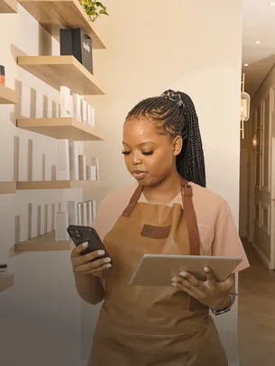 Beauty salon employee using a tablet and phone while a client receives a hair treatment.