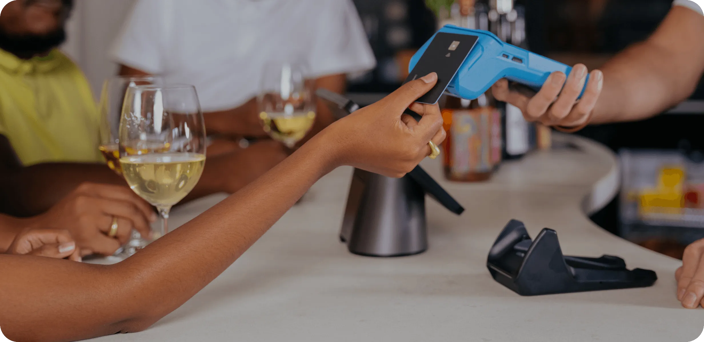 Customer making a payment with a Yoco Khumo portable card machine at a bar or restaurant.