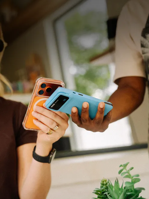 Customer making a contactless payment by tapping a smartphone against a handheld Yoco POS device, demonstrating quick, mobile checkout in a casual retail setting.