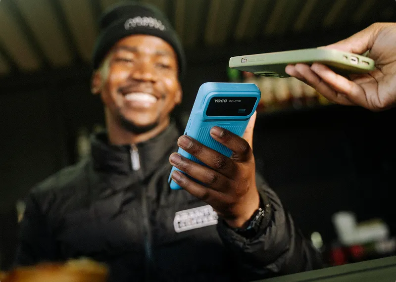 Merchant using a handheld POS device to accept a contactless payment.