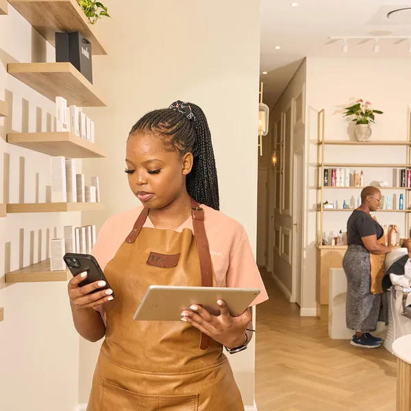 Beauty salon staff managing bookings and sales on a smartphone and tablet