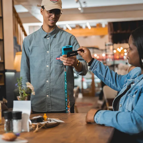 Restaurant customer tapping card on a Yoco mobile card machine for payment